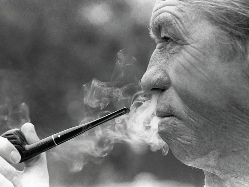 a photograph of a man smoking a pipe in a black and white photo